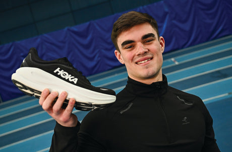A male hold a black Hoka Bondi 9 runner