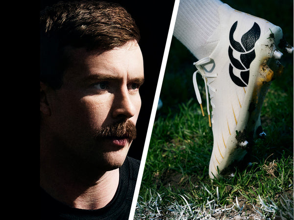 An image of Mack Hansen looking towards the new Canterbury white Rugby boots sitting in the grass with the heel up