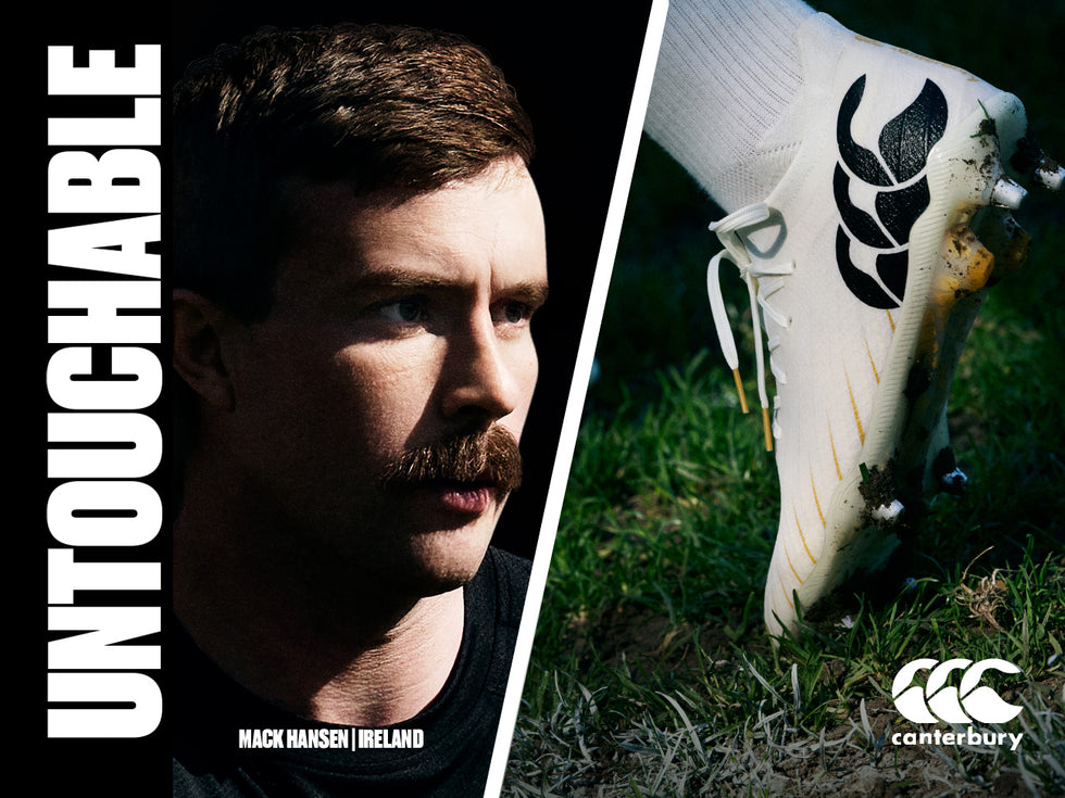An image of Mack Hansen looking towards the new Canterbury white Rugby boots sitting in the grass with the heel up